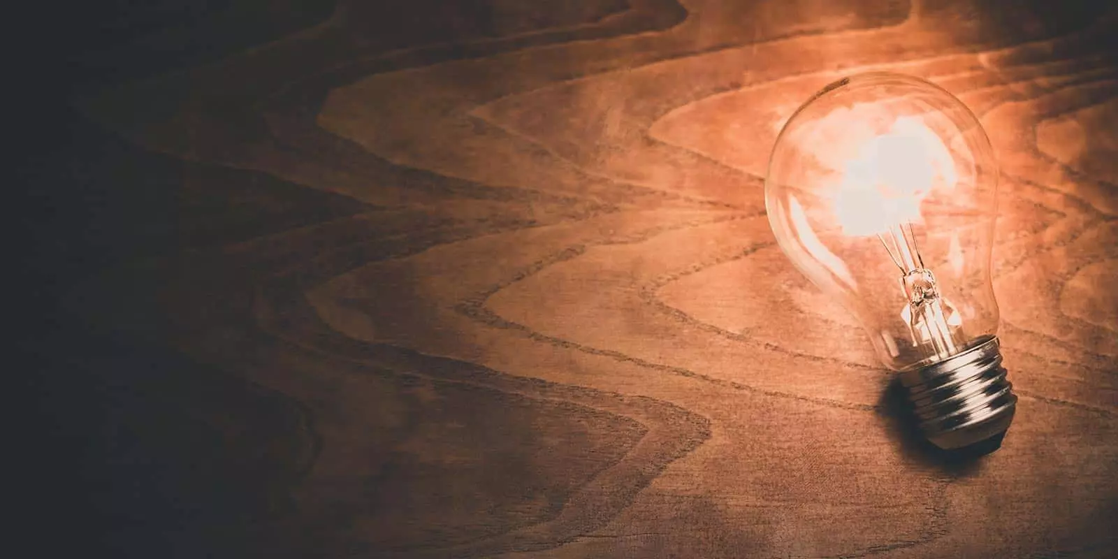 Immagine di una lampadina appoggiata su un tavolo di legno