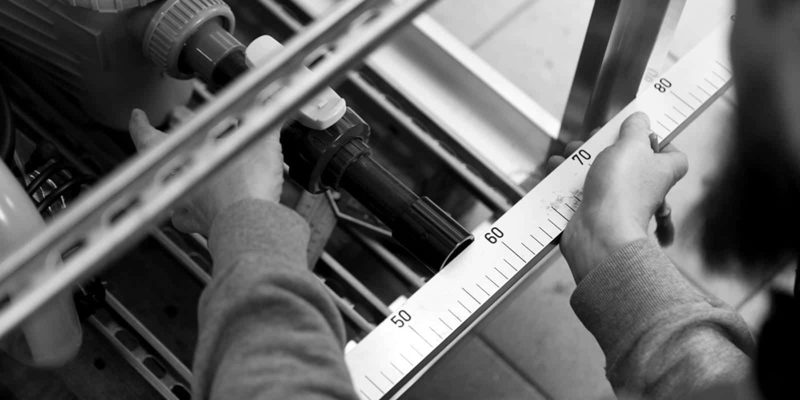 Detail der Hände eines Handwerkers der Hofer Group beim Vermessen eines Teils eines Hydrauliksystems