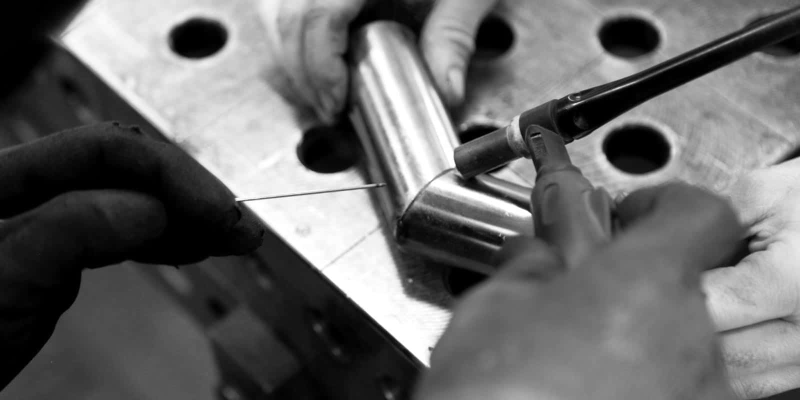 Detail der Hände eines Handwerkers beim Schweißen eines Rohres